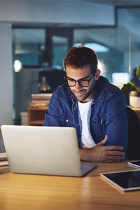 Confident insurance agent attending a virtual meeting on a laptop in a home office environment, planning client strategy or sales outreach.